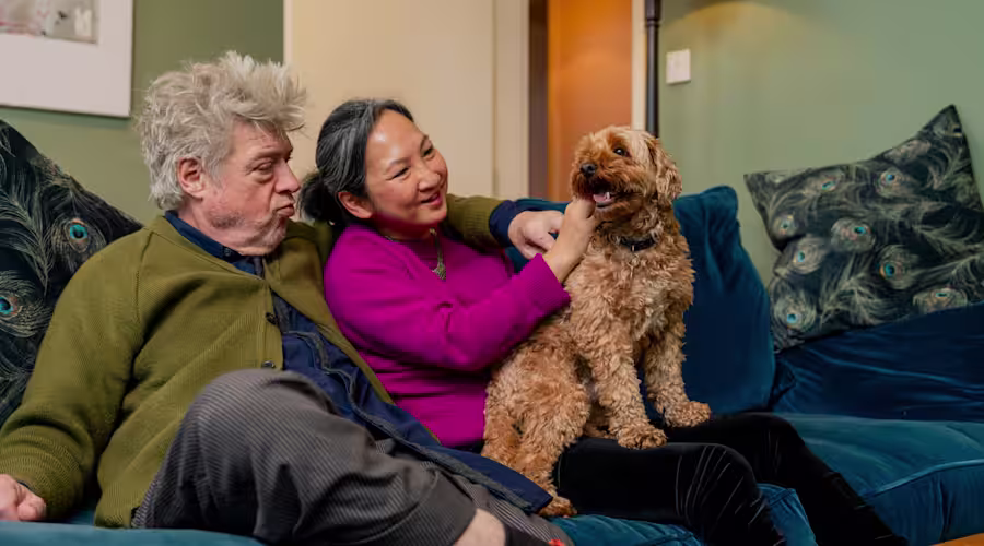 Couple sits on the sofa with a dog